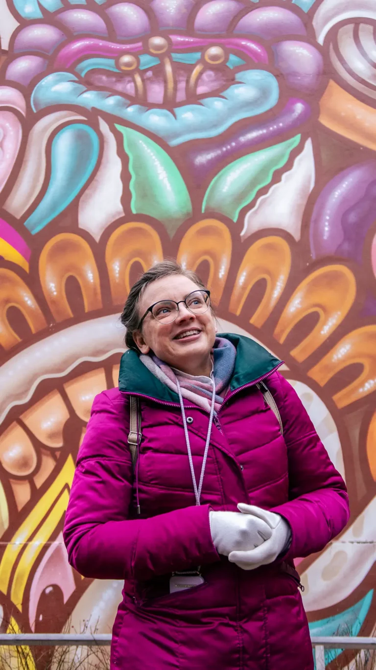 Olesia smiling in front of a colourful mural in Stockholm