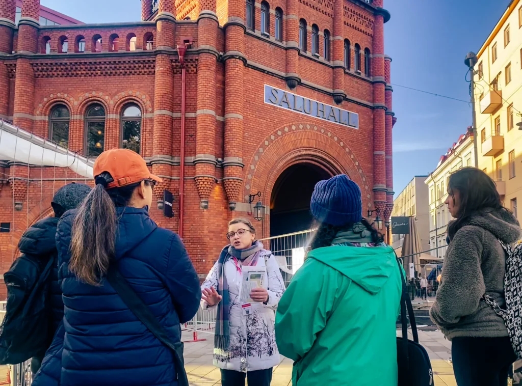 Olesia guiding guests past red-brick buildings in Stockholm