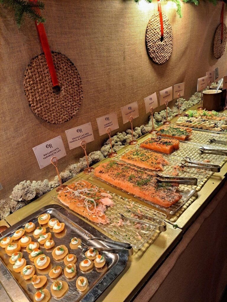 A buffet table of seafood and salmon dishes with woven Christmas decorations on the wall